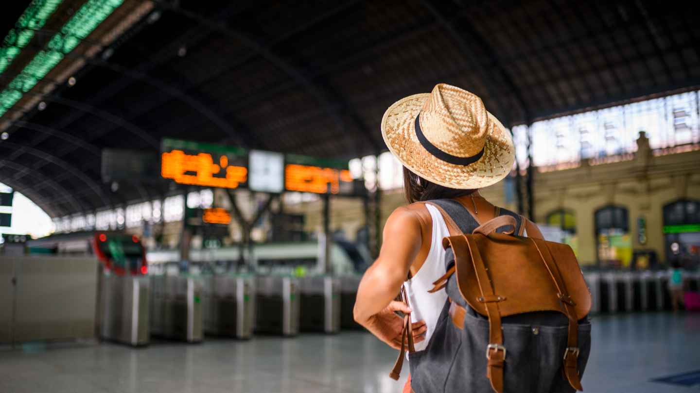 Viaggiatori con bagagli leggeri in una stazione italiana durante un viaggio economico