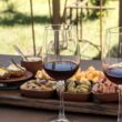 Calici di vino rosso e prodotti locali su un tavolo all’aperto
