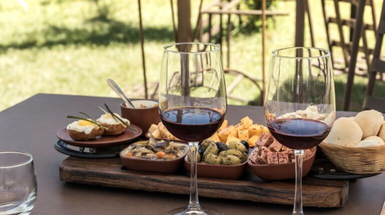 Calici di vino rosso e prodotti locali su un tavolo all’aperto