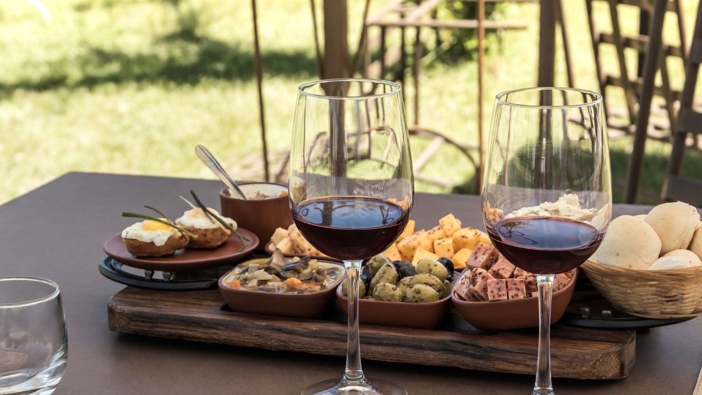 Calici di vino rosso e prodotti locali su un tavolo all’aperto